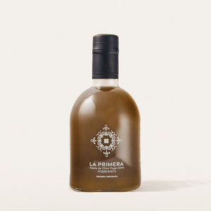Transparent bottle labeled 'LA PRIMERA' Premium Extra Virgin Olive Oil 'Hojiblanca varietal' with Spanish tile logo. 